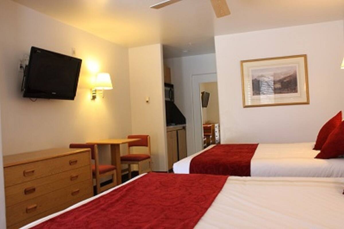 Habitación de hotel con dos camas, televisión, escritorio y una silla.