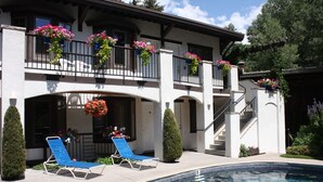 Un edificio de dos pisos con piscina, mobiliario exterior y jardineras en los balcones.