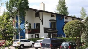 A building with a blue and white facade, multiple parked cars, and a flag.
