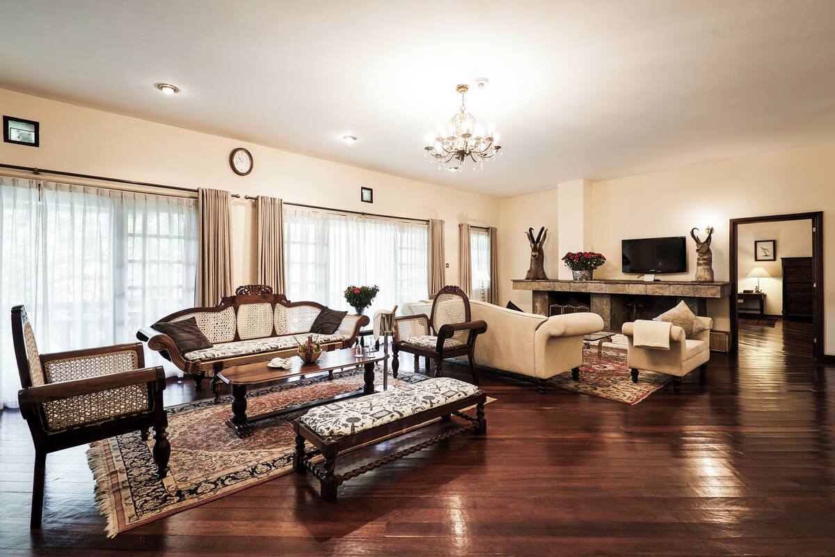 A spacious living room with a large sofa, armchairs, a coffee table, and a fireplace.