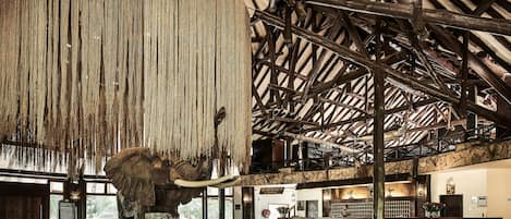 A reception area with a large elephant statue, wooden beams, and a stone wall.