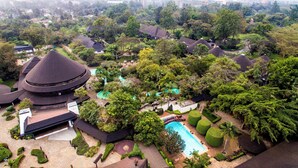 Un resort con varias edificaciones tipo bungalow, una piscina central y exuberante jardinería.