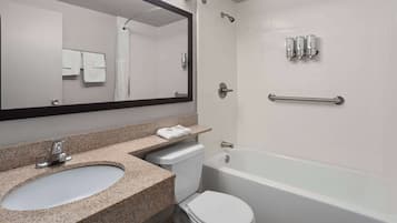 A bathroom with a granite countertop sink, a toilet, a bathtub, a shower, and a mirror.