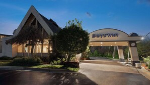 A hotel entrance with a 'Days Inn' sign, a covered driveway, and a well-maintained lawn. - Days Inn by Wyndham Ann Arbor (Ann Arbor)