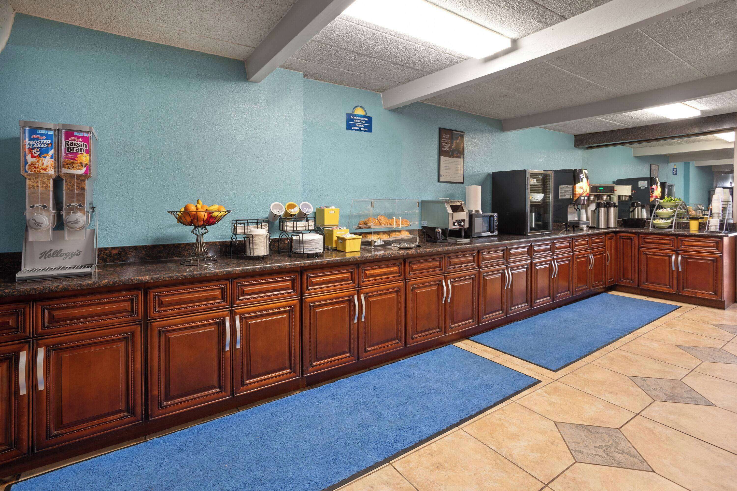 A long counter with a coffee machine, a fruit bowl, and a cereal dispenser.