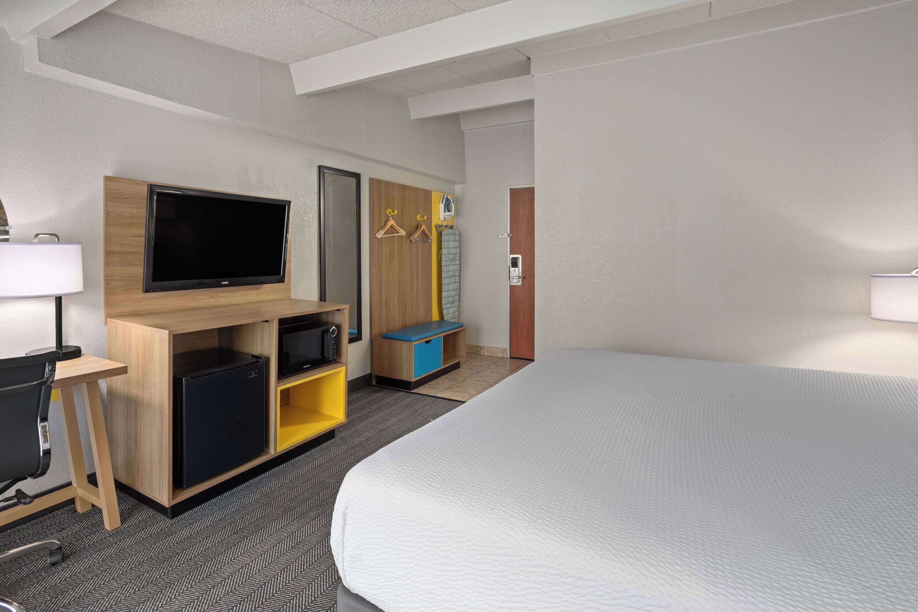 A hotel room with a bed, a TV, a desk, and a wardrobe.