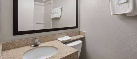 A bathroom with a granite countertop sink, a white toilet, and a mirror above the sink.