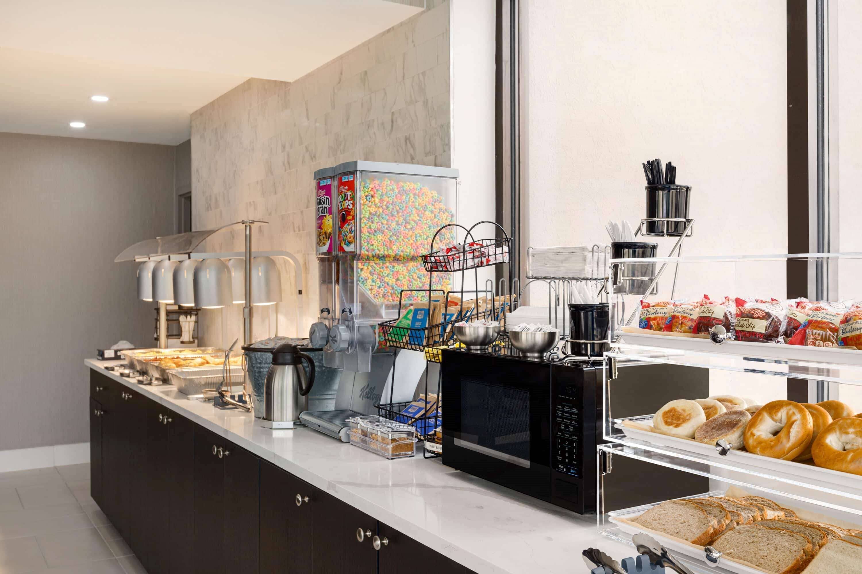 A breakfast buffet with various food items, a coffee machine, and a microwave.