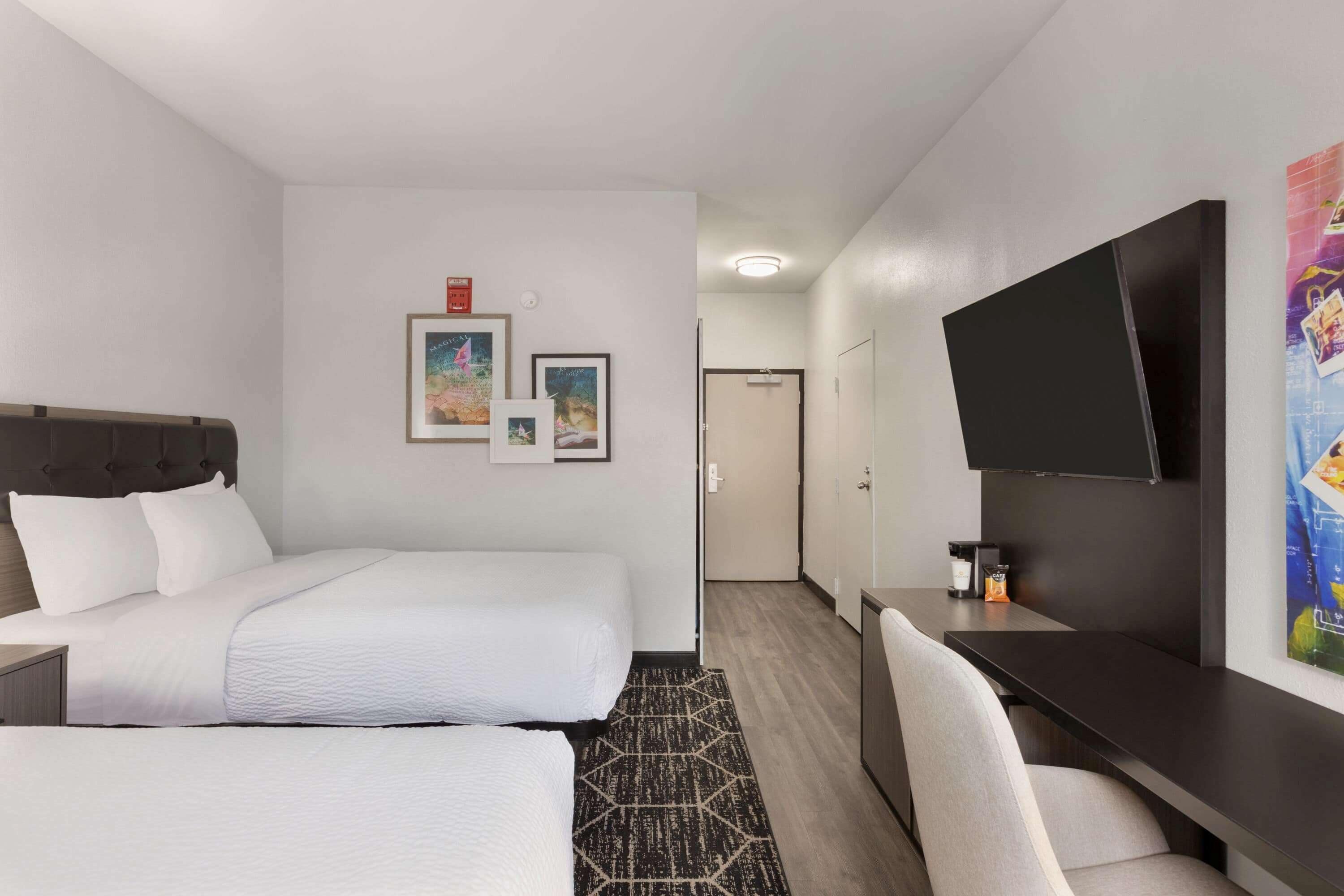 Une chambre d’hôtel comprenant un lit, un bureau, une télévision et une porte donnant accès à une salle de bain.