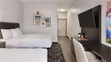 Une chambre d’hôtel comprenant un lit, un bureau, une télévision et une porte donnant accès à une salle de bain.