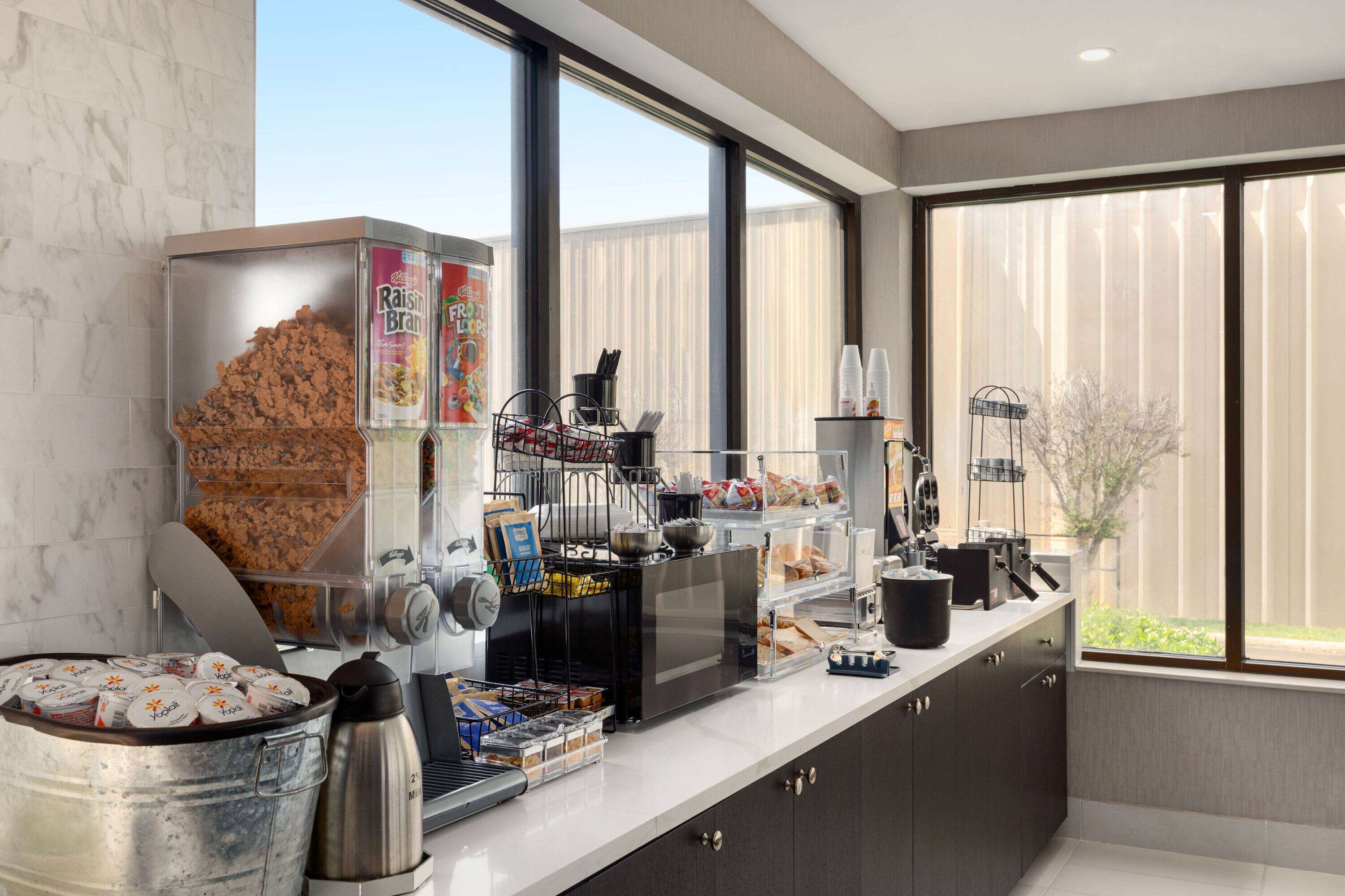 Et moderne køkken med kaffestation, stort vindue og udsigt til naturen.