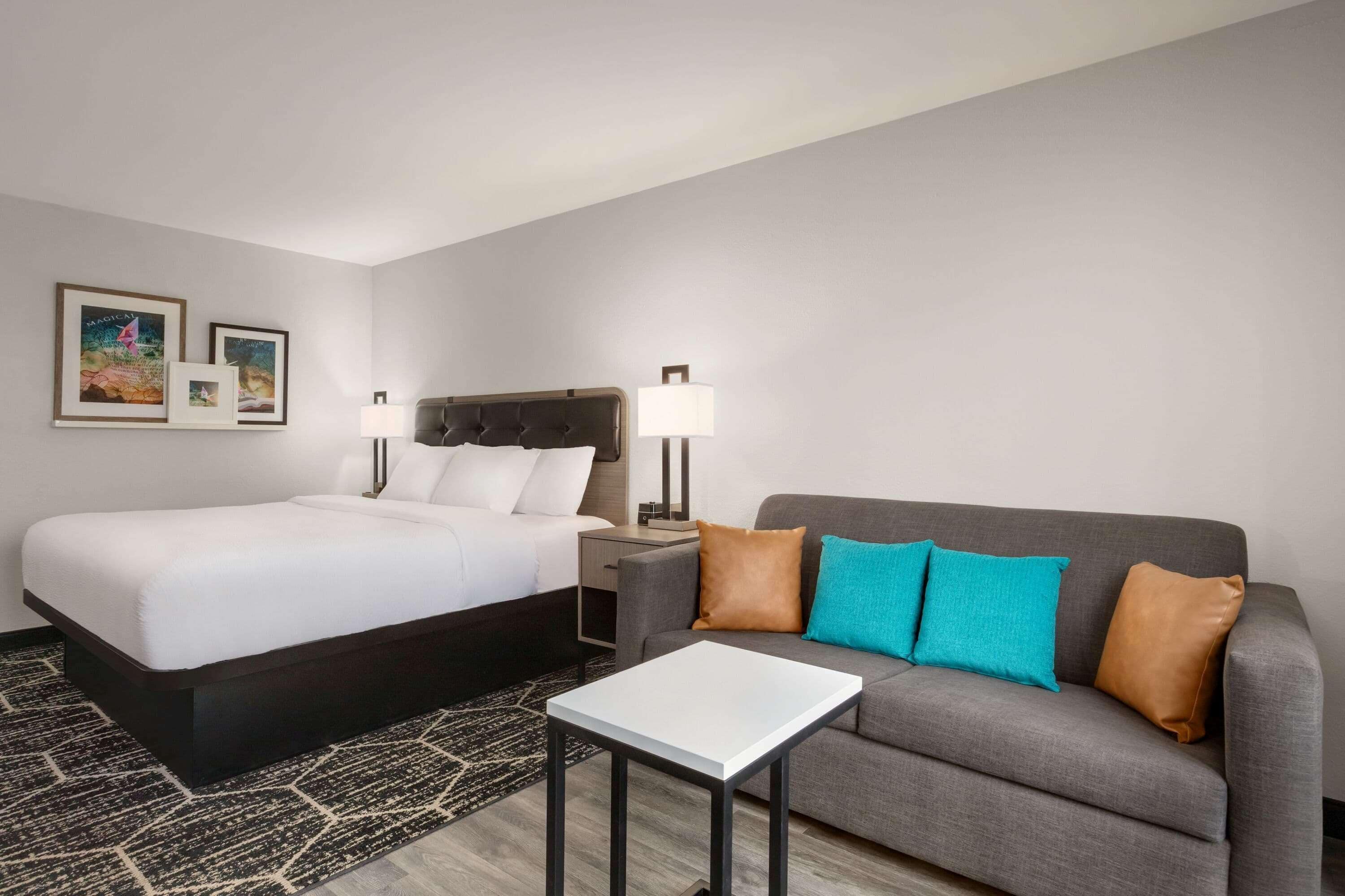 Een hotelkamer met een bed, een bank, een klein tafeltje en twee wandlampen.