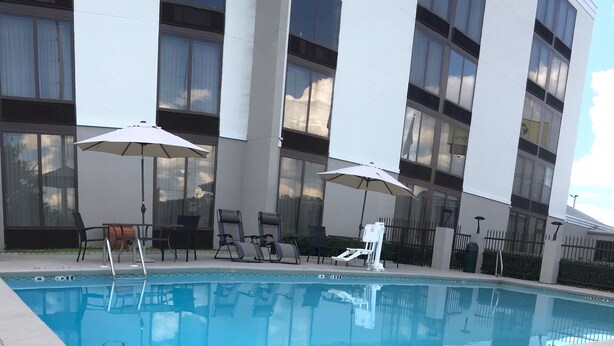 A modern building with a swimming pool, outdoor seating, and umbrellas. - La Quinta Inn & Suites by Wyndham Dothan (Dothan)