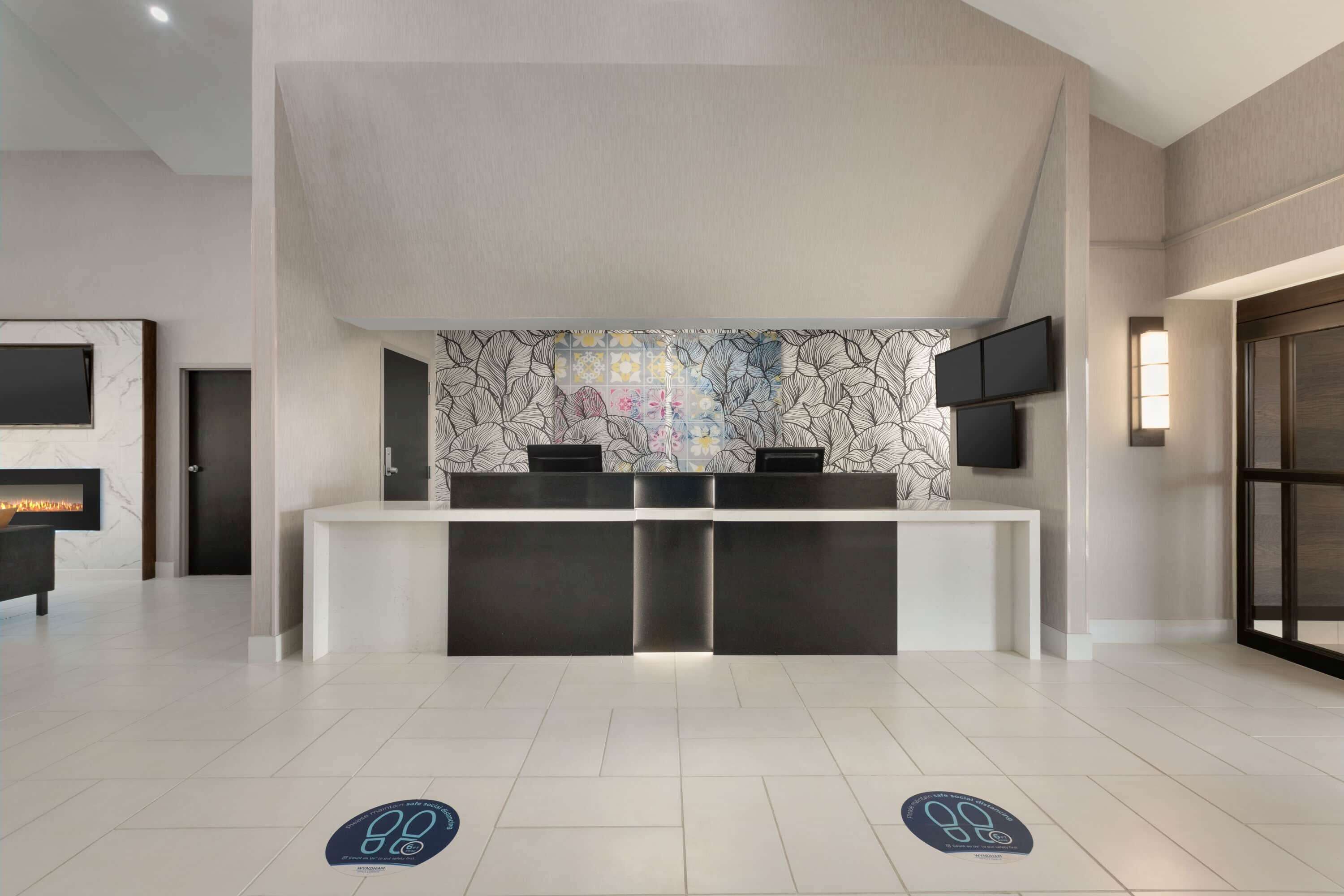 Un espace d’accueil au design moderne, comprenant un mur en marbre, un comptoir d’accueil et un téléviseur à écran plat fixé au mur.