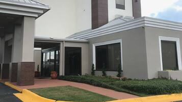 A hotel with a modern design, featuring a prominent entrance with glass doors, a sign reading "LA QUINTA", and a well-maintained lawn area.