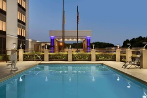 A swimming pool with a view of a building with a flagpole and a fence. - La Quinta Inn & Suites by Wyndham Dothan (Dothan)