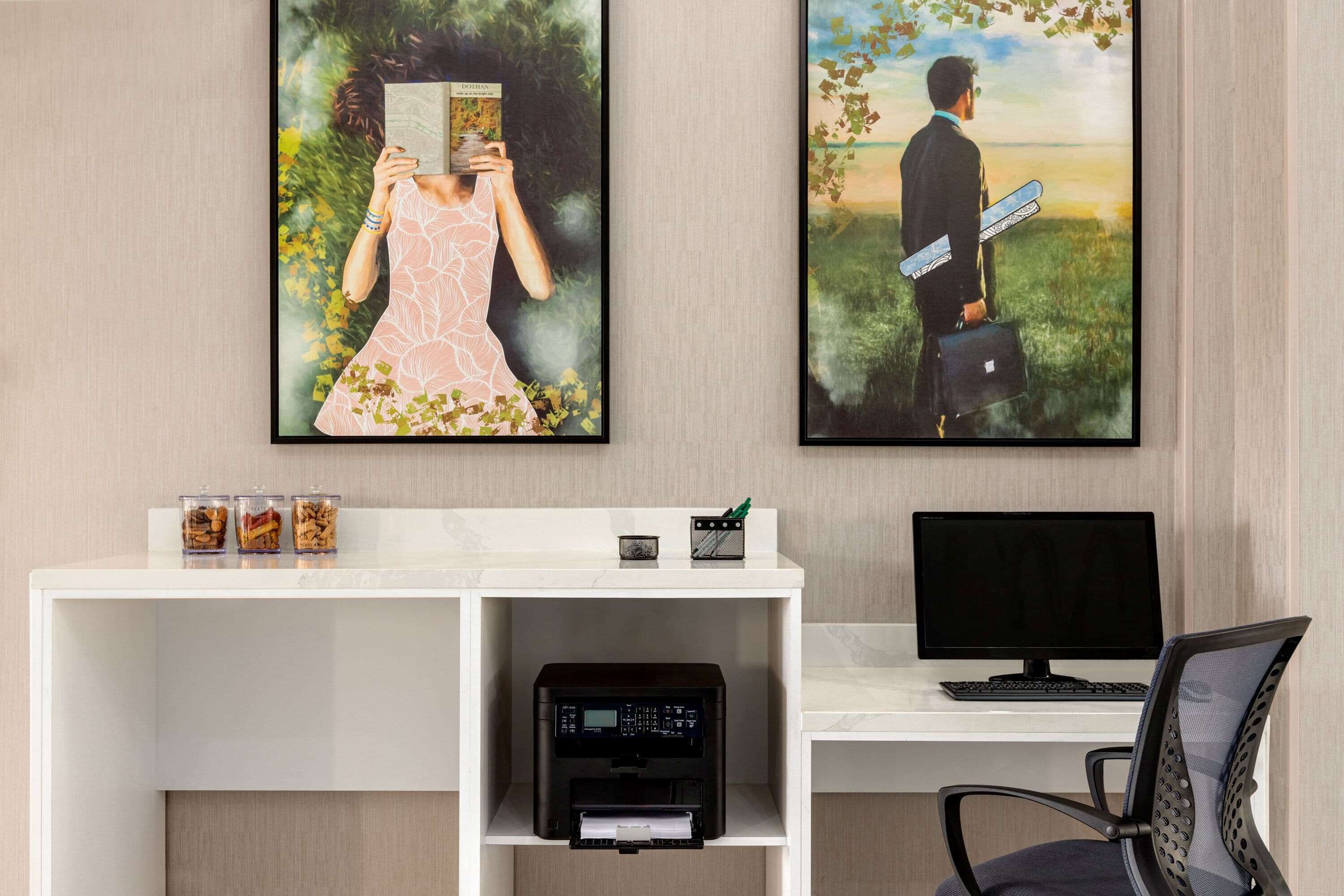 A home office setup with a desk, chair, and two framed artworks on the wall.