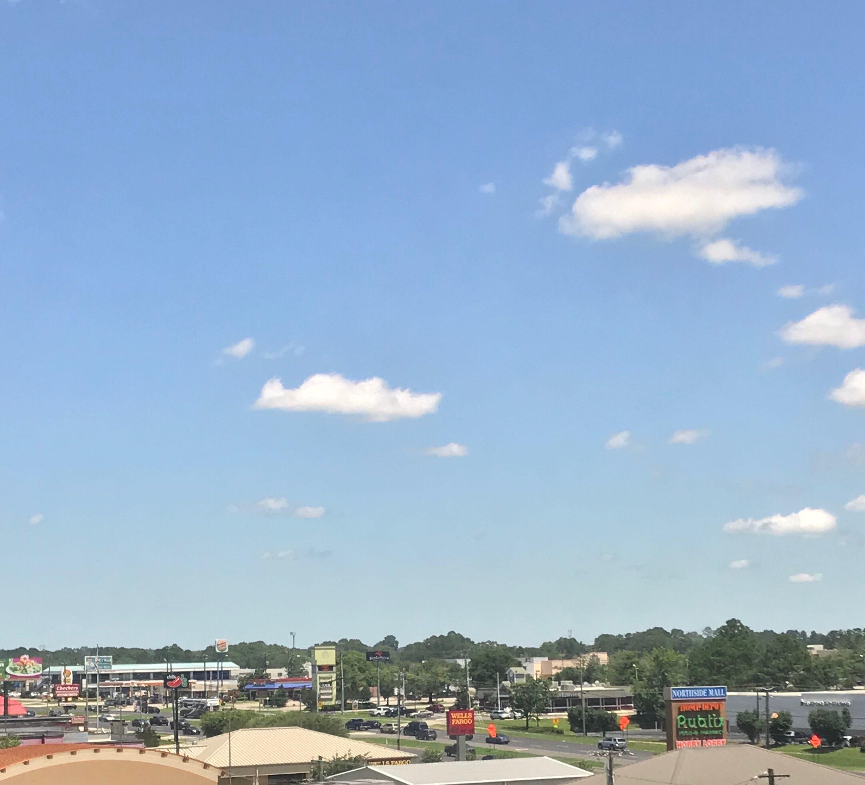 A commercial area with a clear sky, including a large billboard for Northside Mall and a Wells Fargo sign.