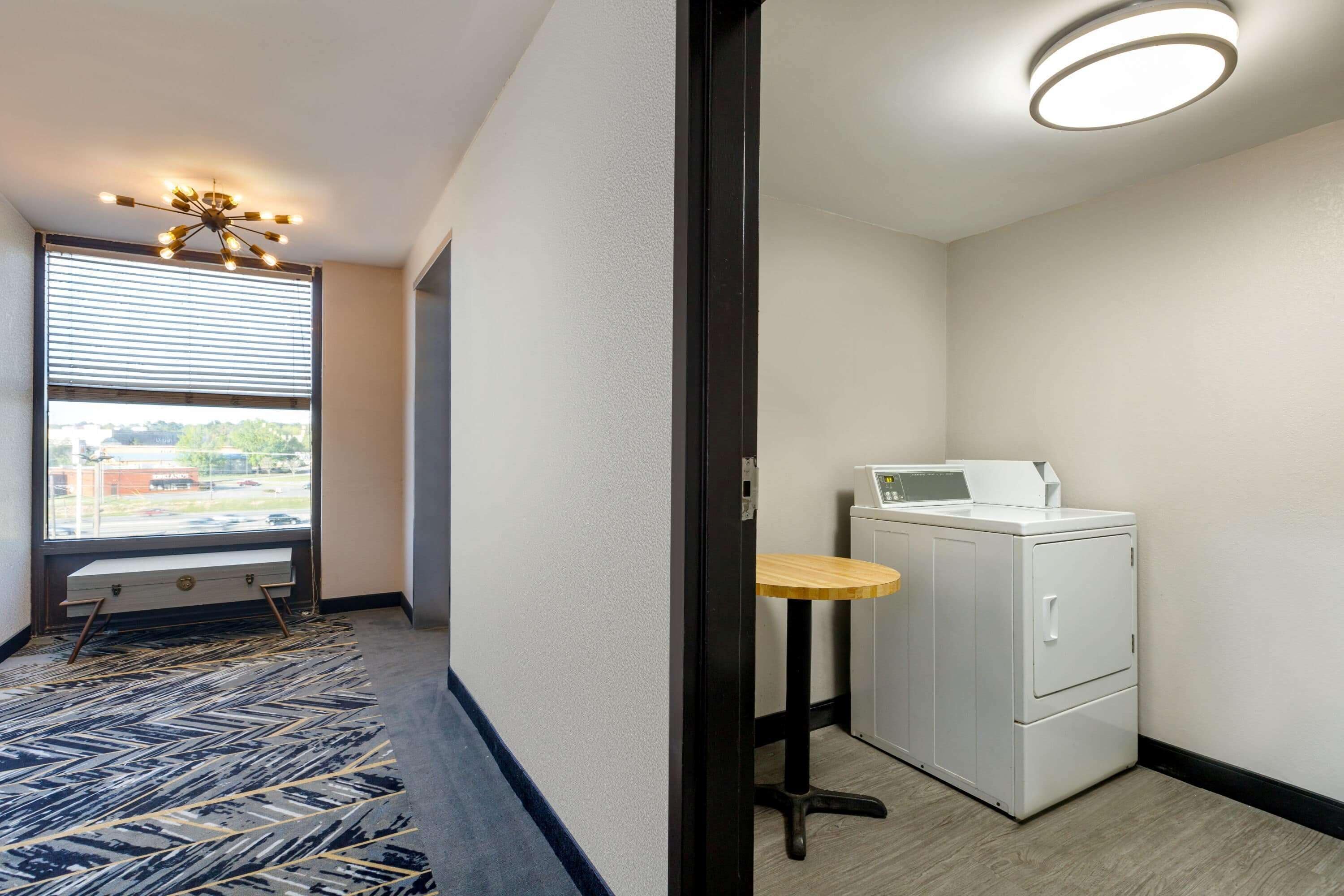 A laundry area with a washing machine, a bench, and a small table.