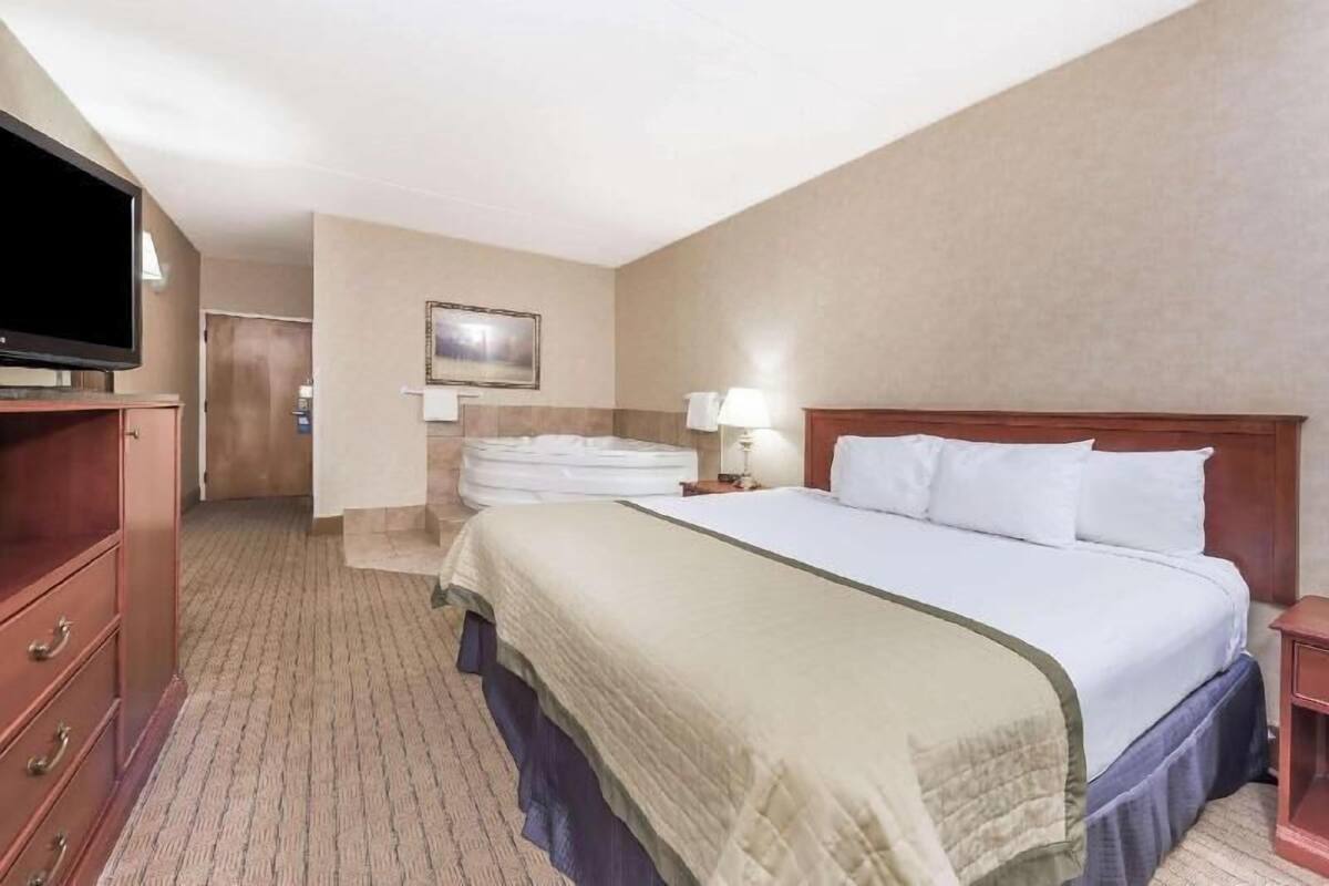 Een hotelkamer met een bed, een televisie, een bureau en een spiegel.
