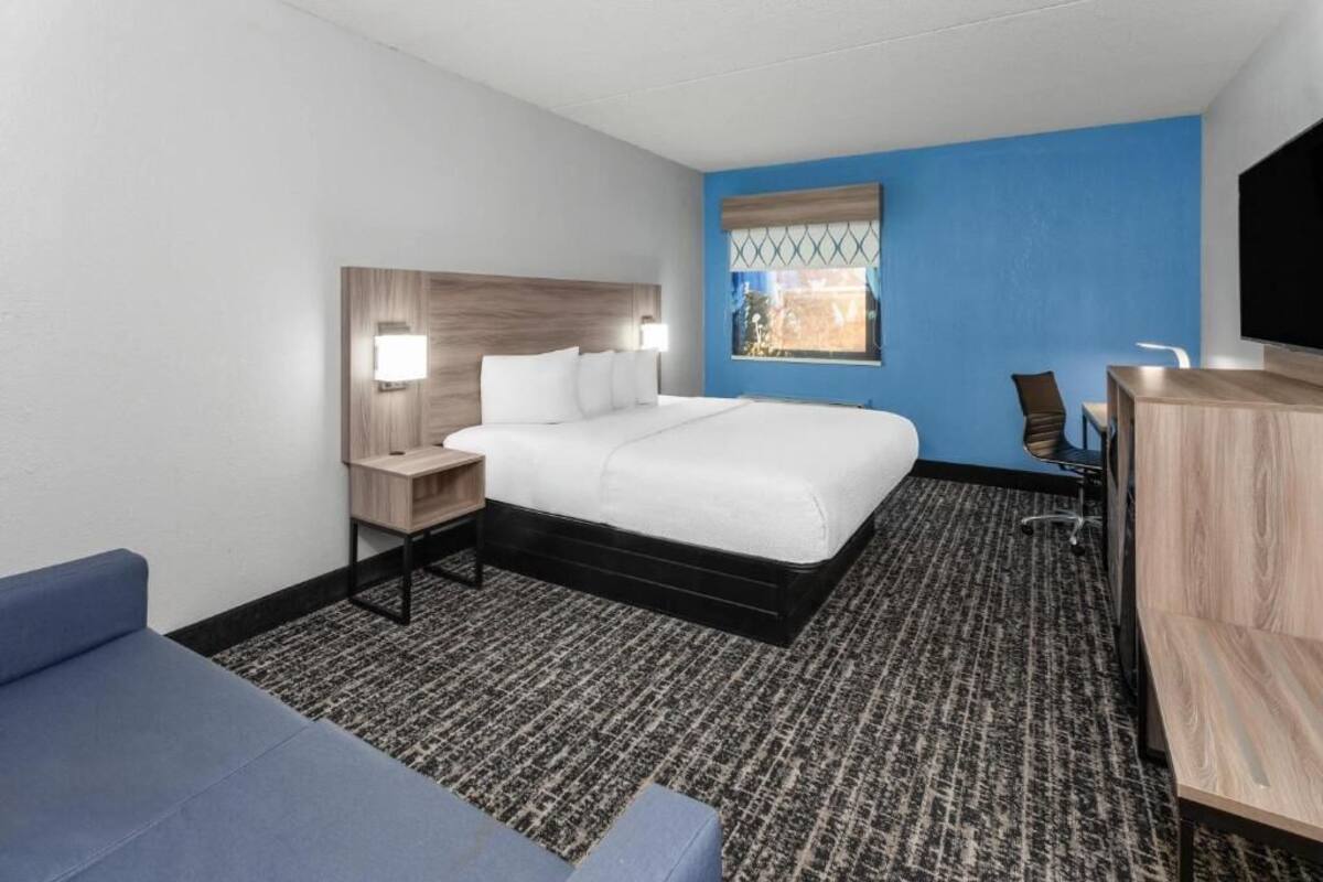 Een hotelkamer met een bed, een bureau, een stoel, een televisie en een raam met uitzicht.