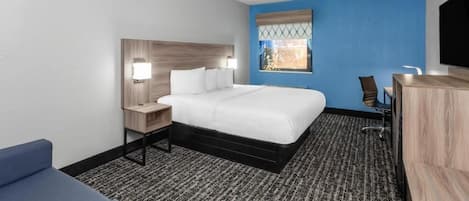 Habitación de hotel con cama, escritorio, silla, televisión y ventana con vistas.