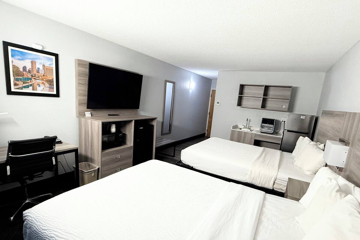 Een hotelkamer met twee bedden, een bureau, een televisie, een minibar en een badkamer.