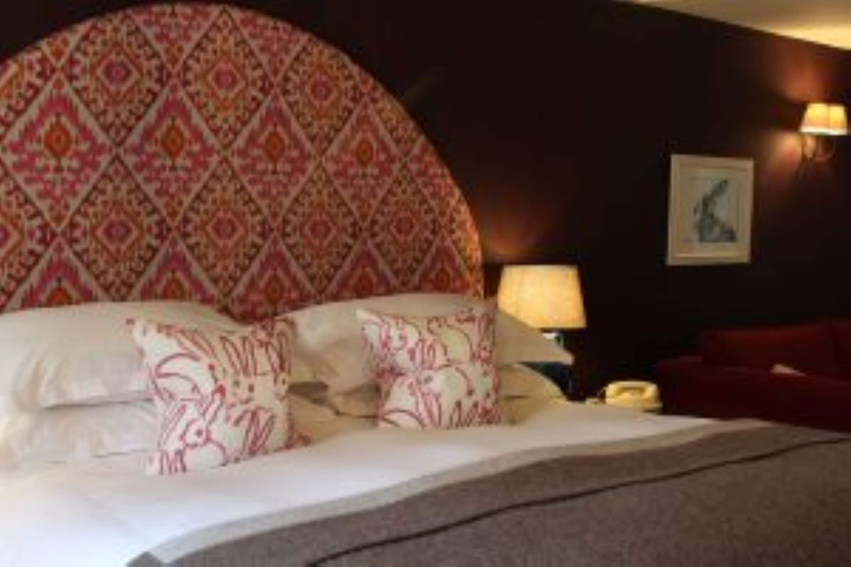 A bed with patterned pillows, a bedside lamp, and a framed picture on the wall.