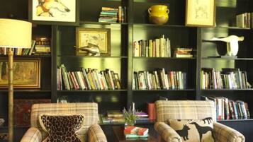 A cozy living room with two plaid armchairs, a coffee table, and a bookshelf filled with books and framed pictures.