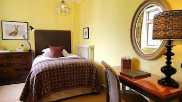 A room with a bed, a desk, a chair, a lamp, and a mirror.