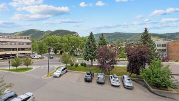 A parking lot with several cars, a building with a flat roof, and a mountainous landscape in the background.