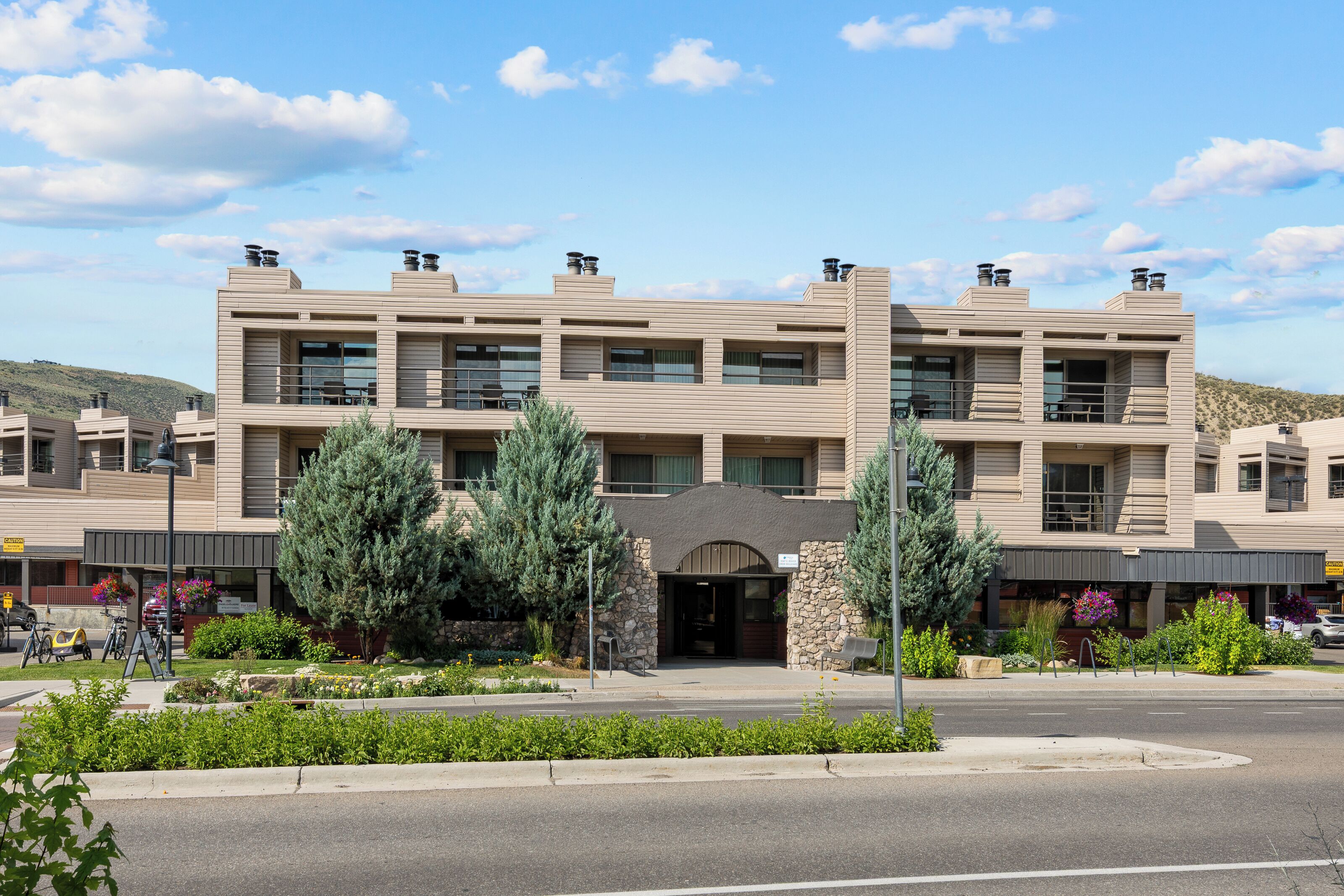A multi-story hotel with a flat roof, large windows, and a landscaped front yard.