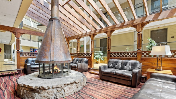 A lobby with a stone fire pit, leather sofas, and a wooden ceiling structure. - The Christie Lodge - All Suite Property, Vail Valley/Beaver Creek (Avon)