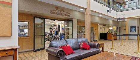A lobby with a leather sofa, wooden coffee table, and a carpeted floor.