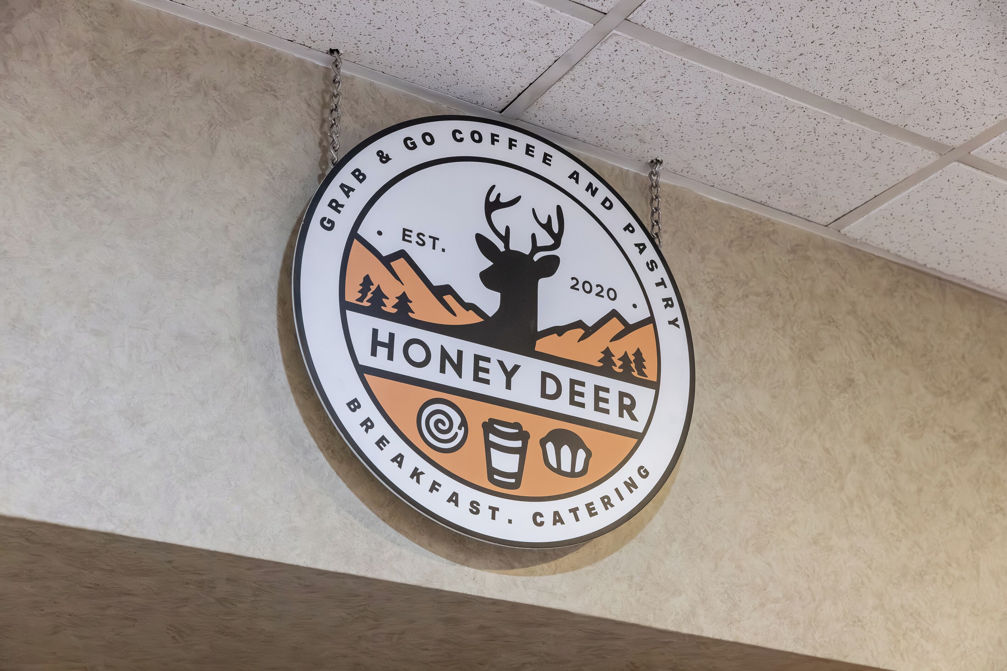 A circular logo with a deer and mountains, indicating a brand related to breakfast and catering.
