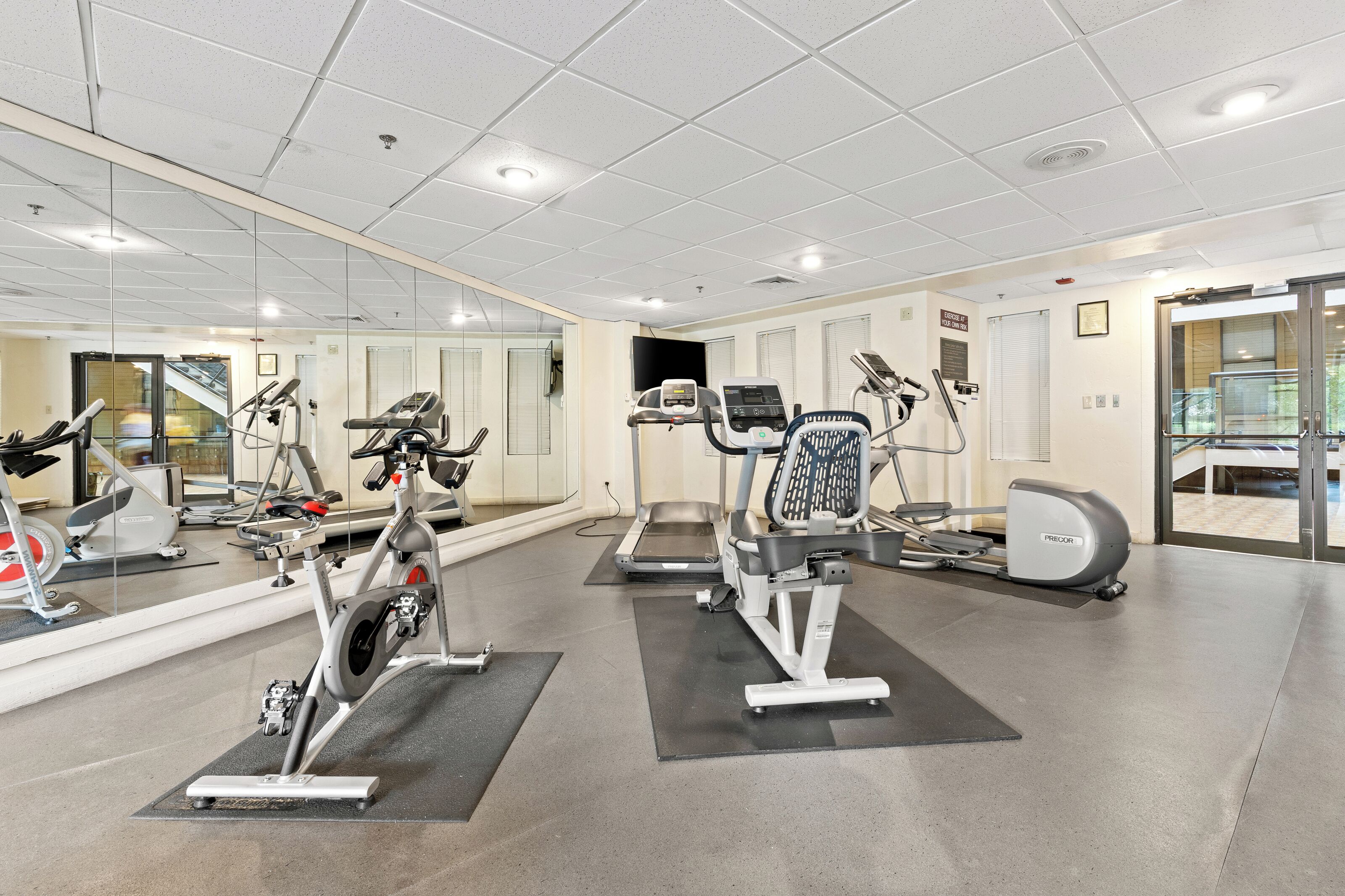 Une salle de sport équipée de divers appareils d’exercice, notamment des tapis de course, des vélos d’appartement et des appareils de musculation.