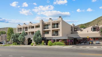 A multi-story hotel with a flat roof, a central entrance, and a parking area in front.