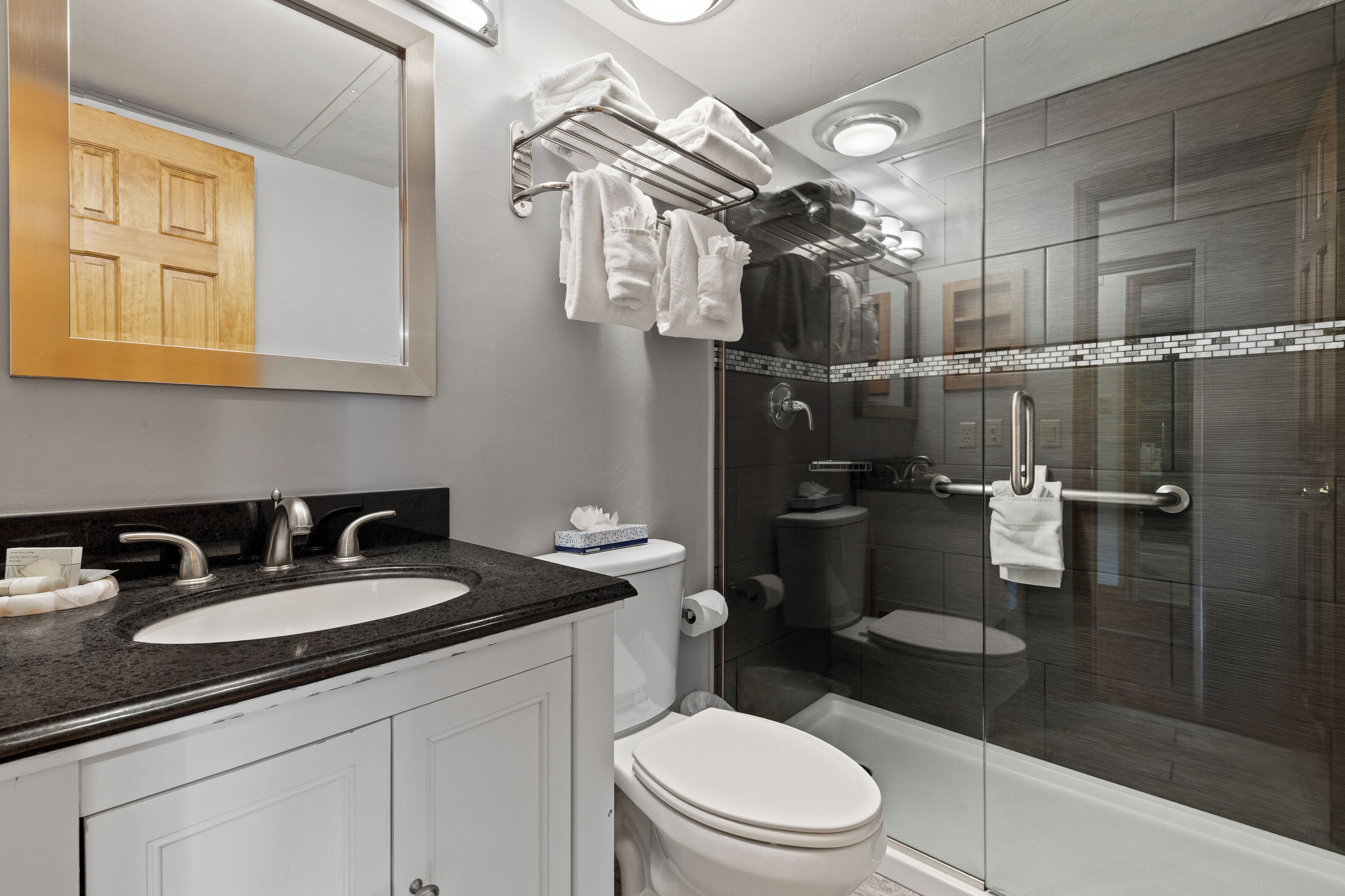 A modern bathroom with a glass-enclosed shower, a double sink vanity, and a toilet.