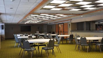 A conference room with multiple tables and chairs, carpeted floor, and a ceiling with fluorescent lights.