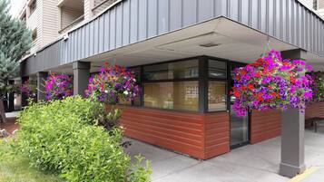 A modern building with a covered entrance area, large windows, and hanging flower baskets.