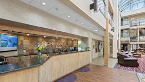 A reception area with a wooden counter, a large screen displaying a scenic view, and a sign reading "The Christie Lodge." - The Christie Lodge - All Suite Property, Vail Valley/Beaver Creek (Avon)