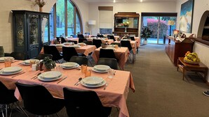 A dining area with tables set for a meal, a large arched window, and a view of the outdoors. - Riverbank Park Motel (Bright)