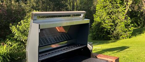 An outdoor grill with a brick base, a metal grate, and a control panel with knobs.