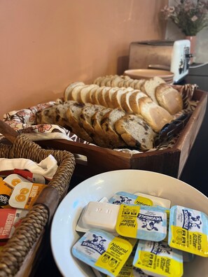 Un bufé con pan en rodajas, mantequilla y mermelada.