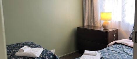 Une chambre d’hôtel avec deux lits, une table de chevet, une lampe et un tableau encadré au mur.