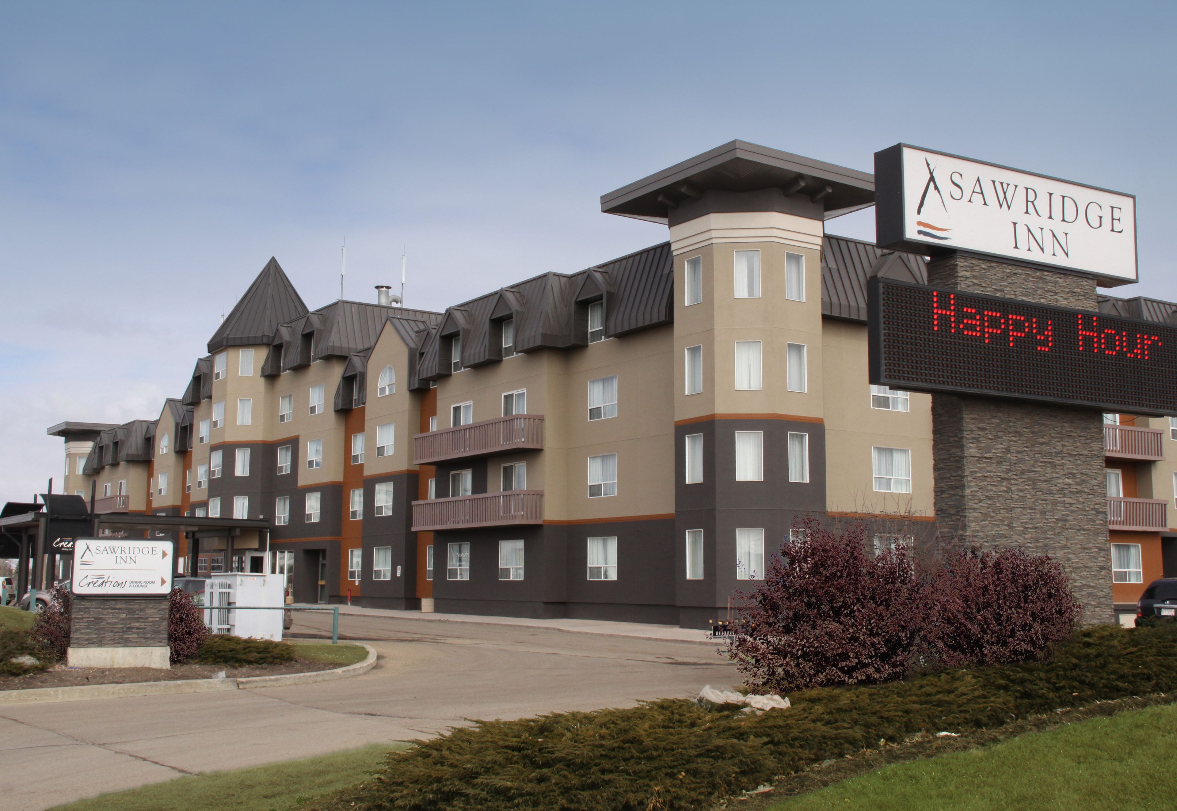 A multi-story hotel with a sign reading "SAWRIDGE INN" and a digital display saying "Happy Hour".