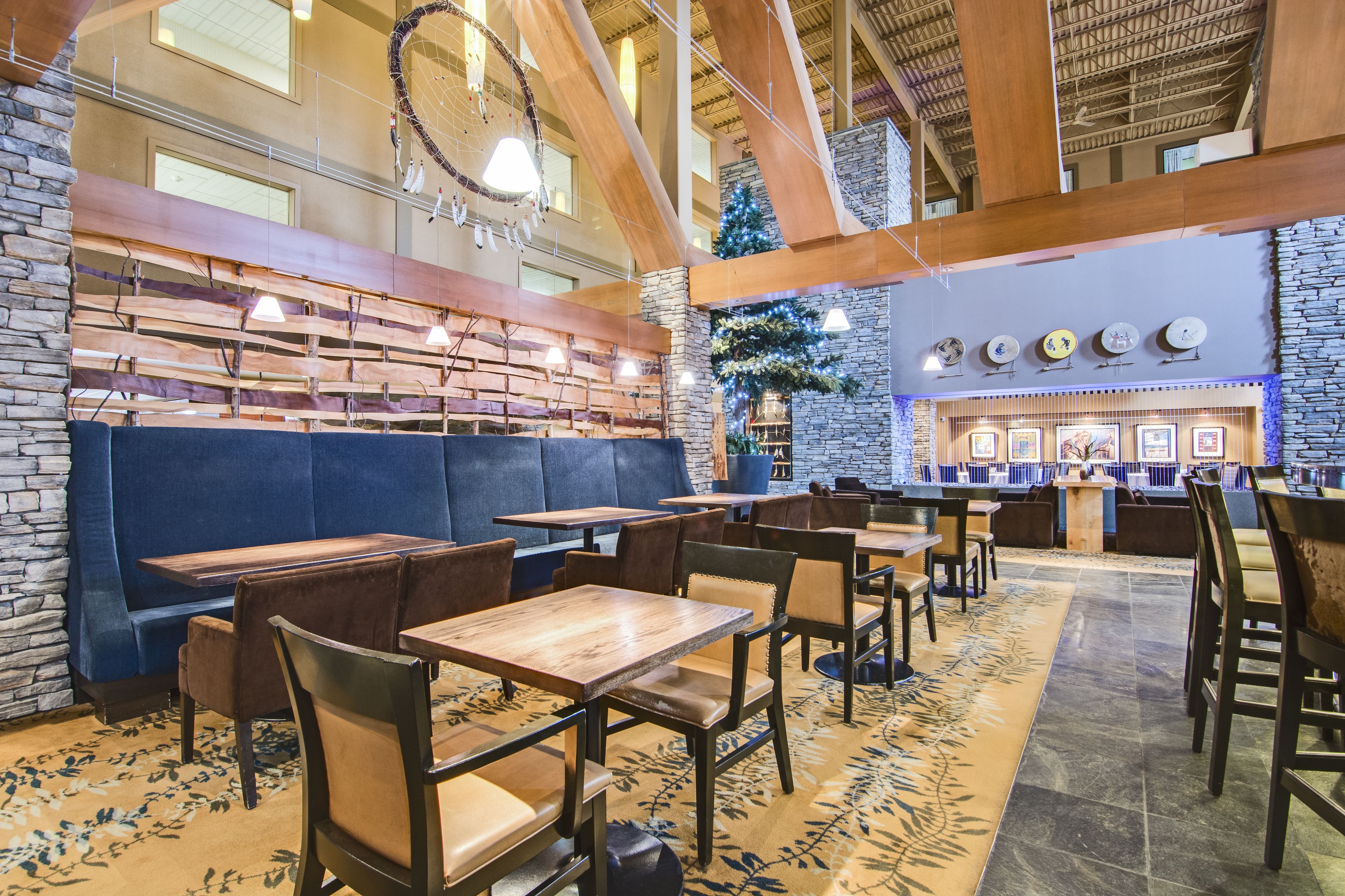 A restaurant with wooden tables and booths, stone walls, and a Christmas tree.