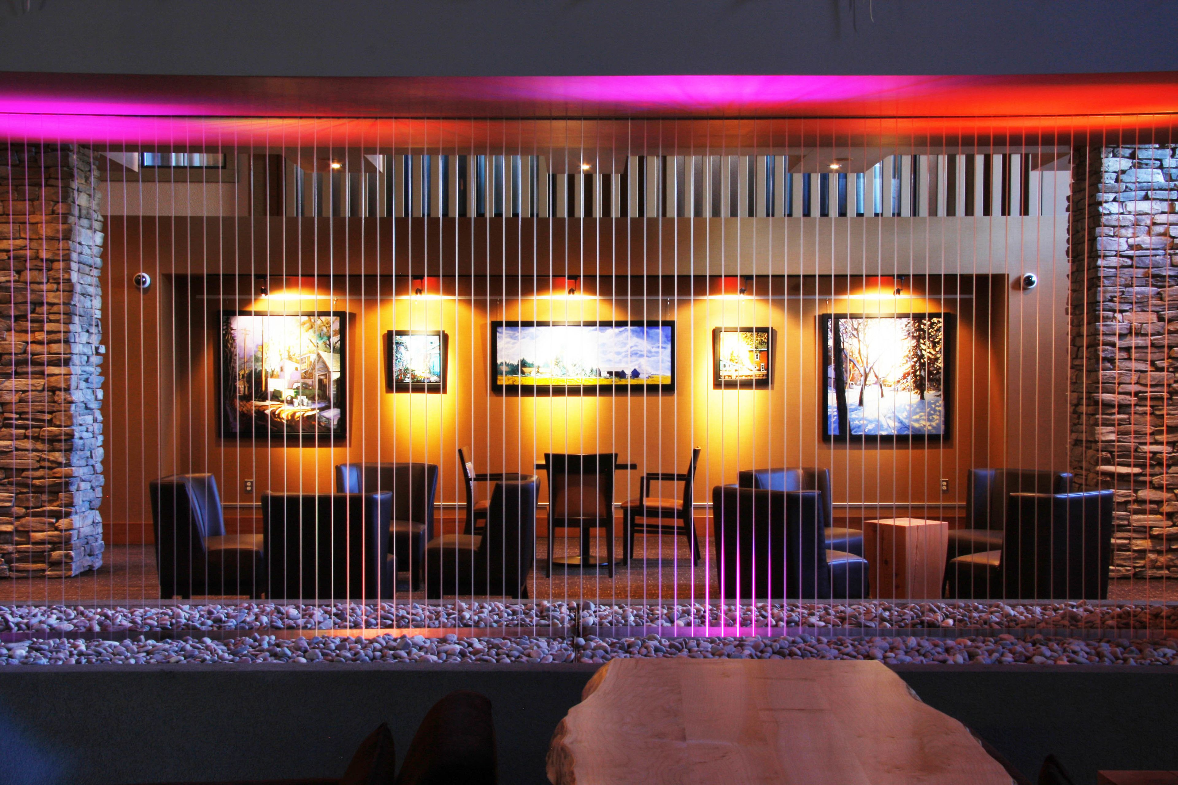 A modern lounge area with a stone wall, a wooden table, and multiple seating arrangements.