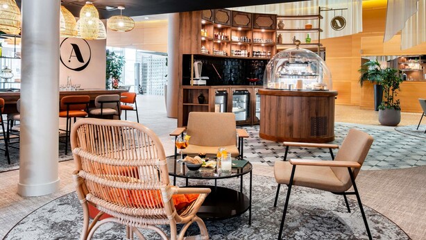 Un intérieur moderne avec des chaises en osier, un coin bar et une grande colonne.