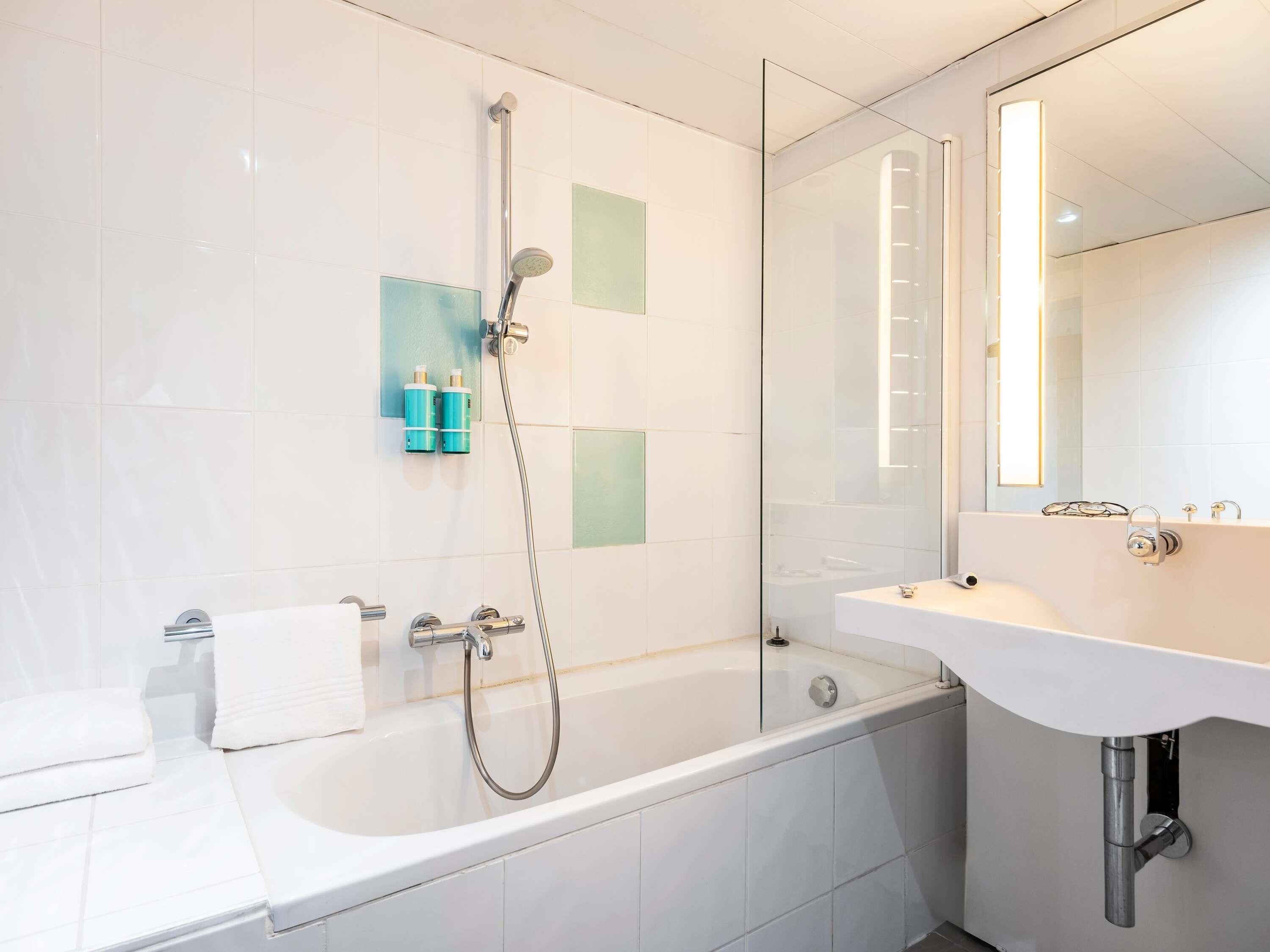 A modern bathroom with a bathtub, shower, and sink.